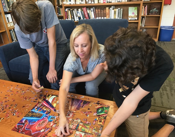 Jacob Tadlock (far left) and Shea Colborn tackle the latest puzzle with Mrs. Nishiya as part of Puzzle Club -- Photo by Fred Alvarez